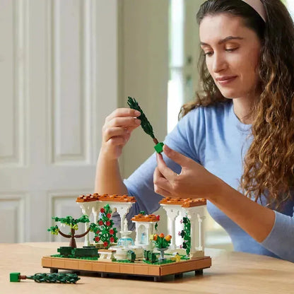 Person assembling a 2TTOYS Lego botanical garden set featuring colorful flowers and detailed architecture