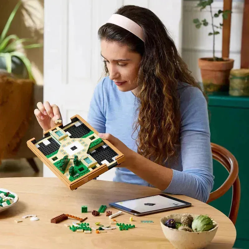 Woman assembling the lego botanical garden set with colorful pieces on a wooden table