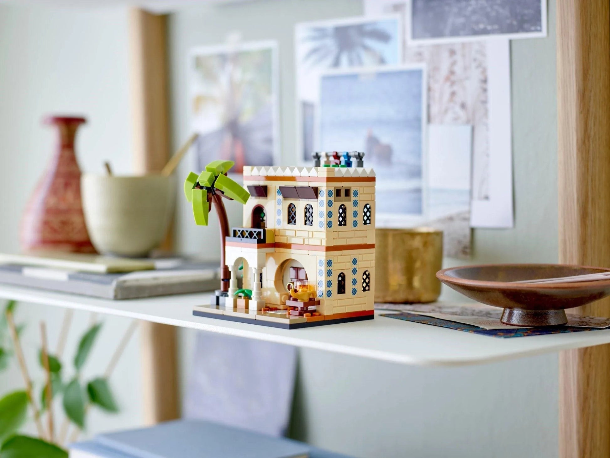 Colorful LEGO houses model on a shelf with decorative items and photos in the background