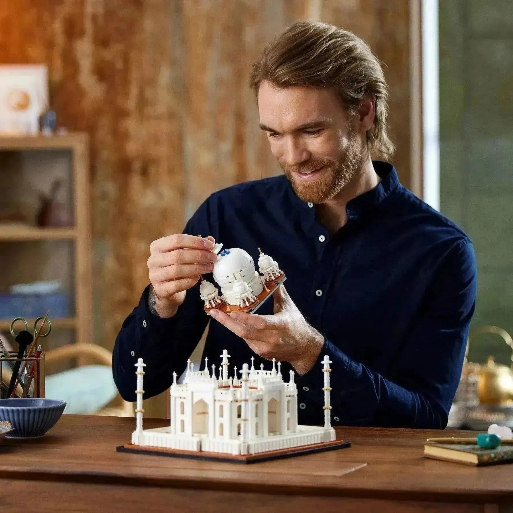 Person assembling a LEGO Architecture Taj Mahal model with intricate details and design elements